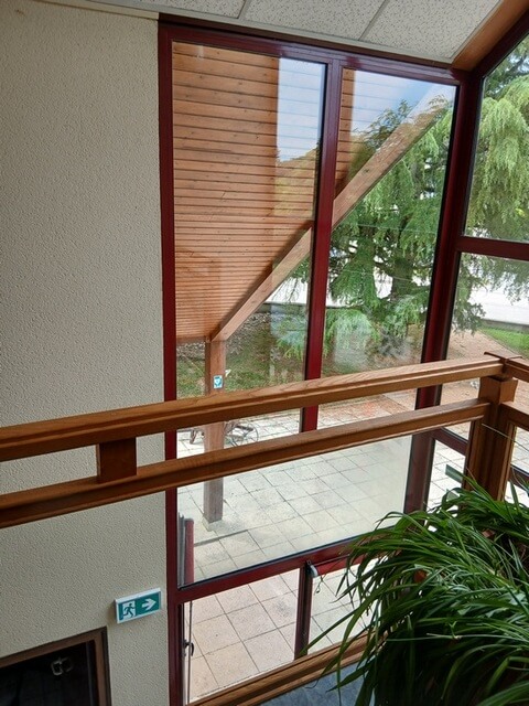 Nettoyage vitres dole pour baie vitrée avec rambarde en bois intérieure et vue sur l'extérieur.